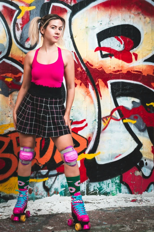 a young woman posing with her skateboard near a graffiti covered wall