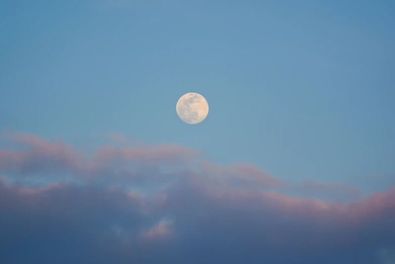 the moon in the night sky is just behind some clouds