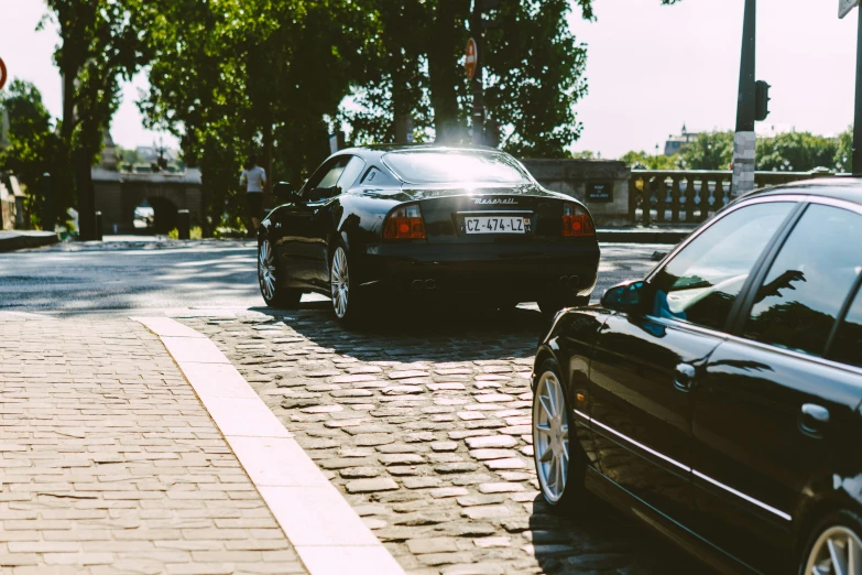 a black car on the road near another one