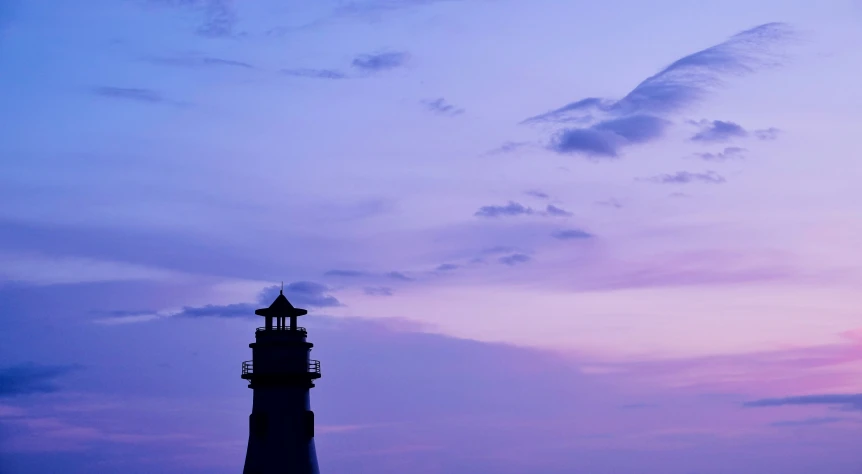 a large light house against a purple sky at twilight