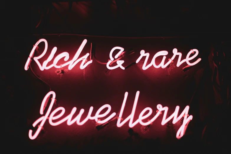 a red neon sign reads rich & rare jewelry