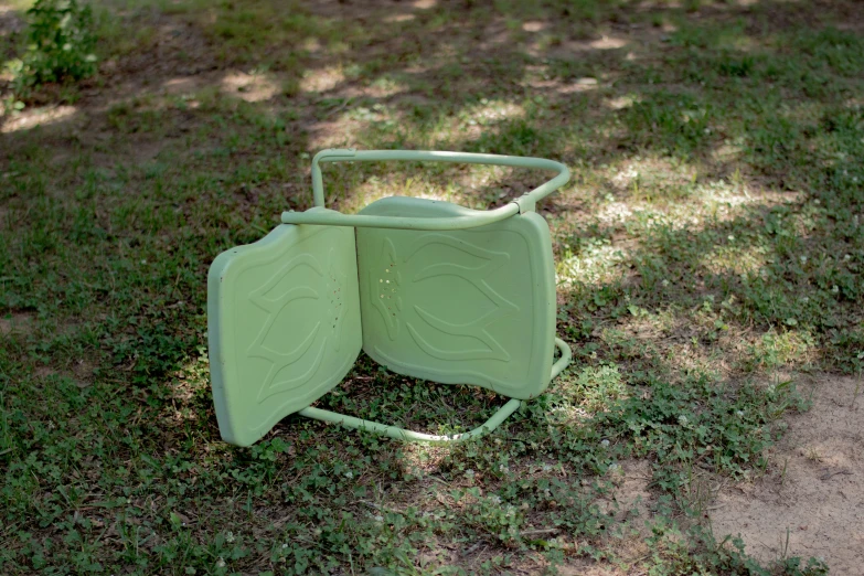 a green plastic chair laying on the ground
