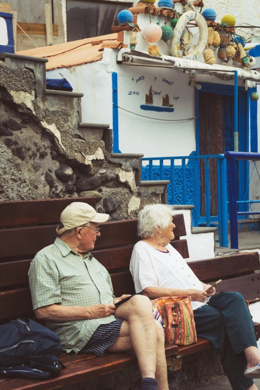 two people sit on a bench outside in front of a building