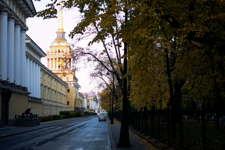 the view of an old city street with tall buildings and trees