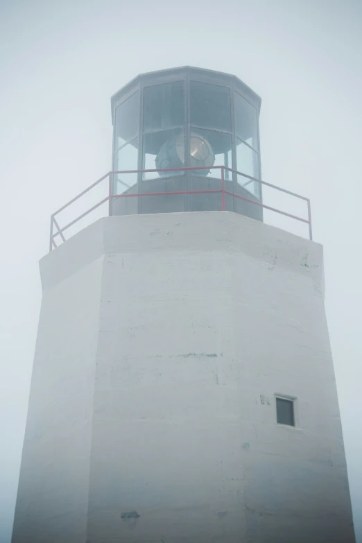 a light house standing in the fog with a large circular bell above it