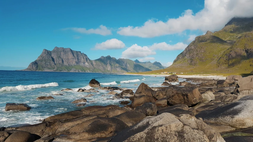 an ocean shoreline with large rocks in the foreground