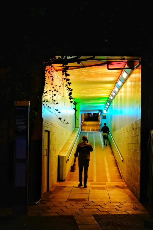 two people are walking under the rainbow tunnel