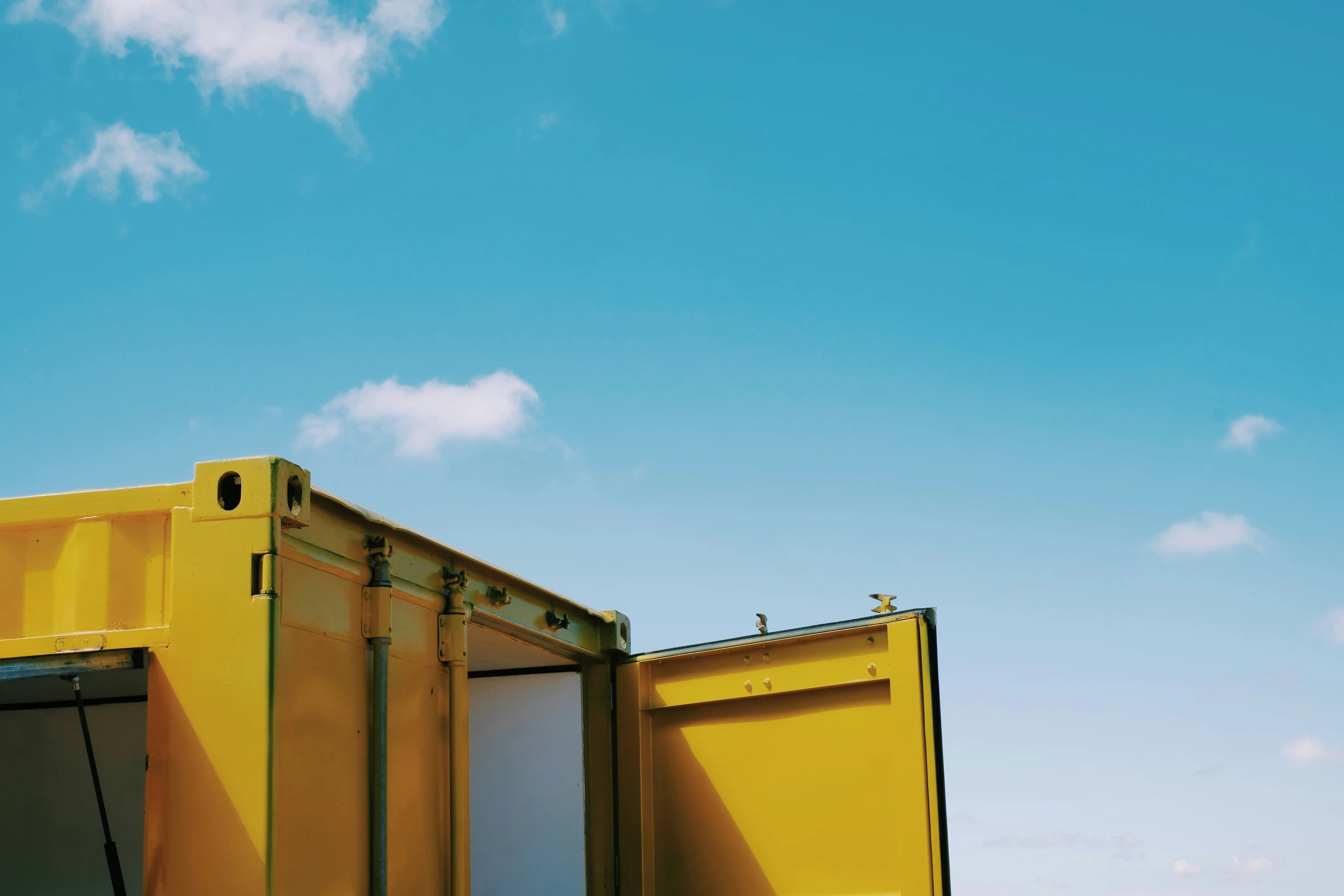 the side of a yellow dumpster has the door open