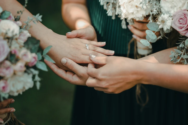 a woman holding onto a bride's hand and touching her finger with another