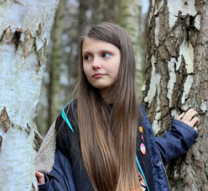 a  stands in front of several trees, looking off to the side