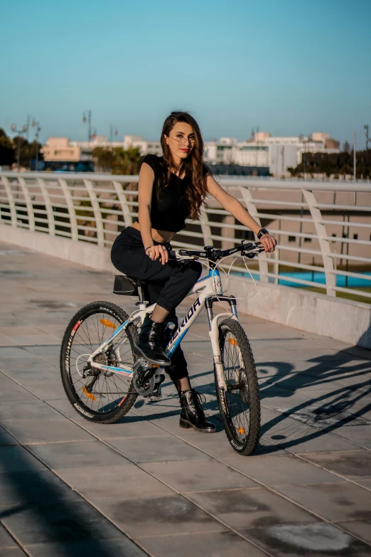 the girl is sitting on her bike at the bridge