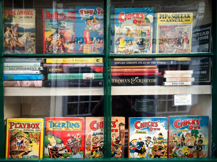 a shelf full of comics on display behind glass
