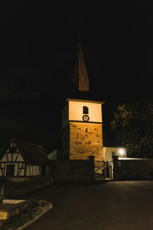 an old stone church steeple with a lighted clock at night