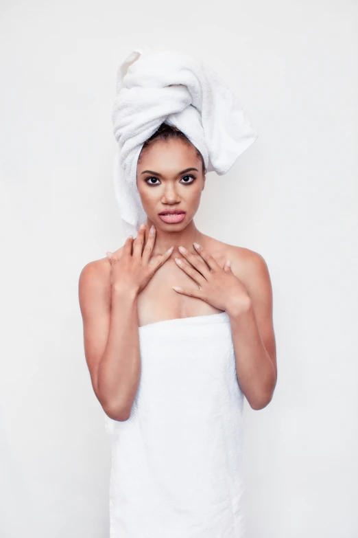 woman in towel wrapped over head holding her hands over her chest