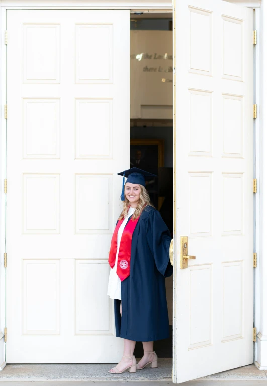 a female graduate is standing in the doorway