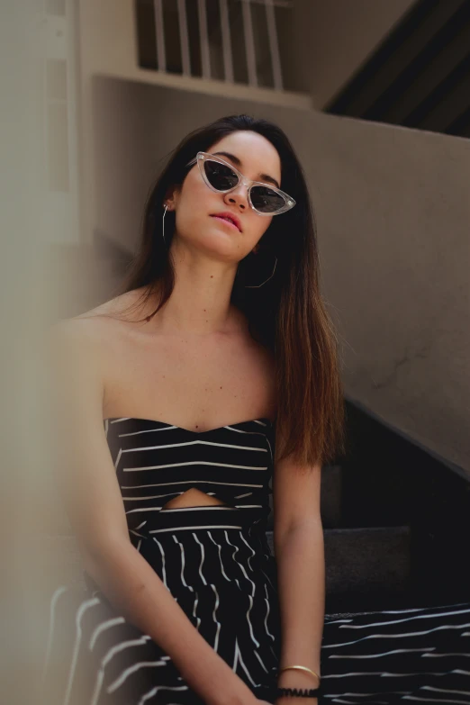 a beautiful young woman sitting down in her striped dress