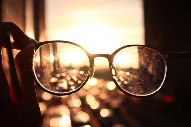 a woman is looking through her glasses as the sun sets