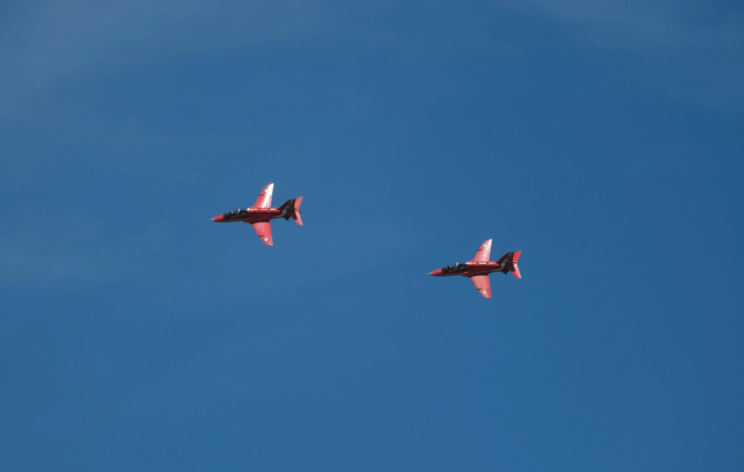 two airplanes are flying in formation overhead against a blue sky