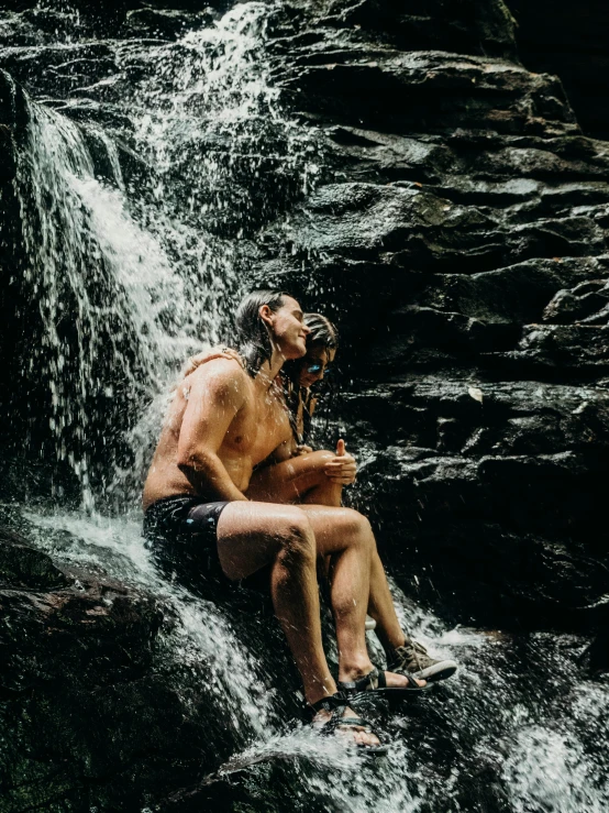 a man sitting on the edge of a waterfall with water gushing from his face