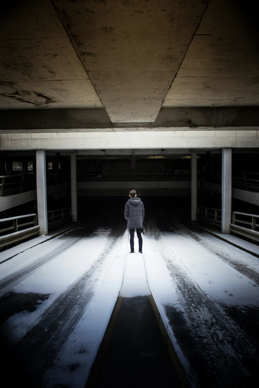 a person standing in a parking garage with his skateboard