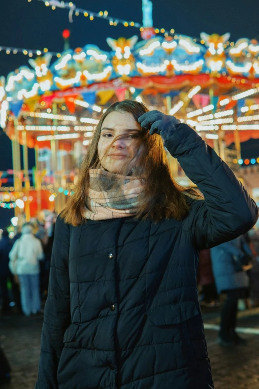 woman with tattooed hand near carnival ride at night