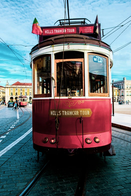 a red and white tram car sitting on top of a stone road