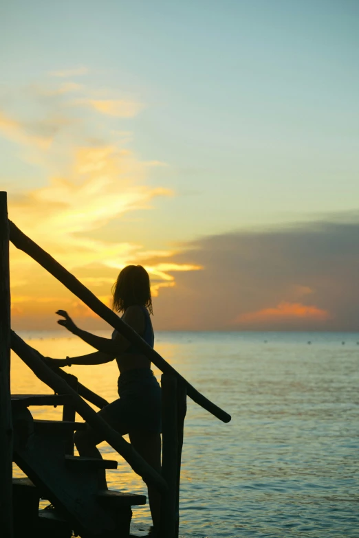 the silhouette of a woman on stairs watching the sunset