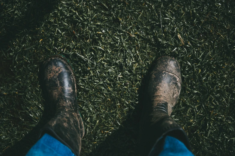 the top view of a persons feet with shoes and blue jeans