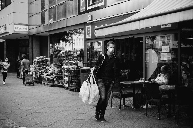 a man carrying two bags of groceries walking through an outside market