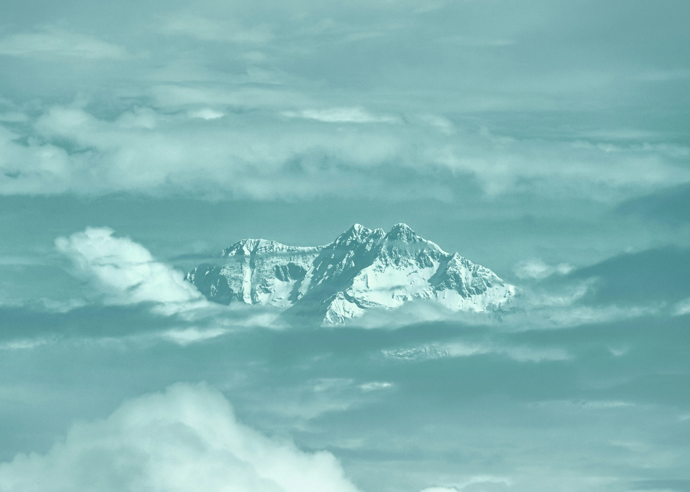 snow capped mountain is obscured by white clouds