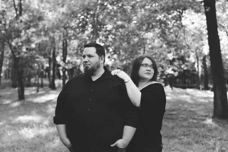 a couple standing under trees in the woods together