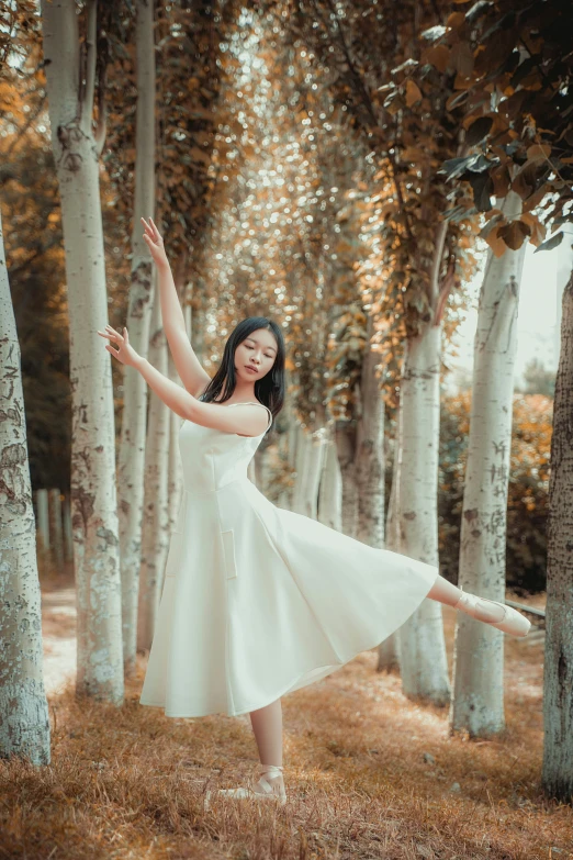 woman standing in forest surrounded by trees reaching for the tree