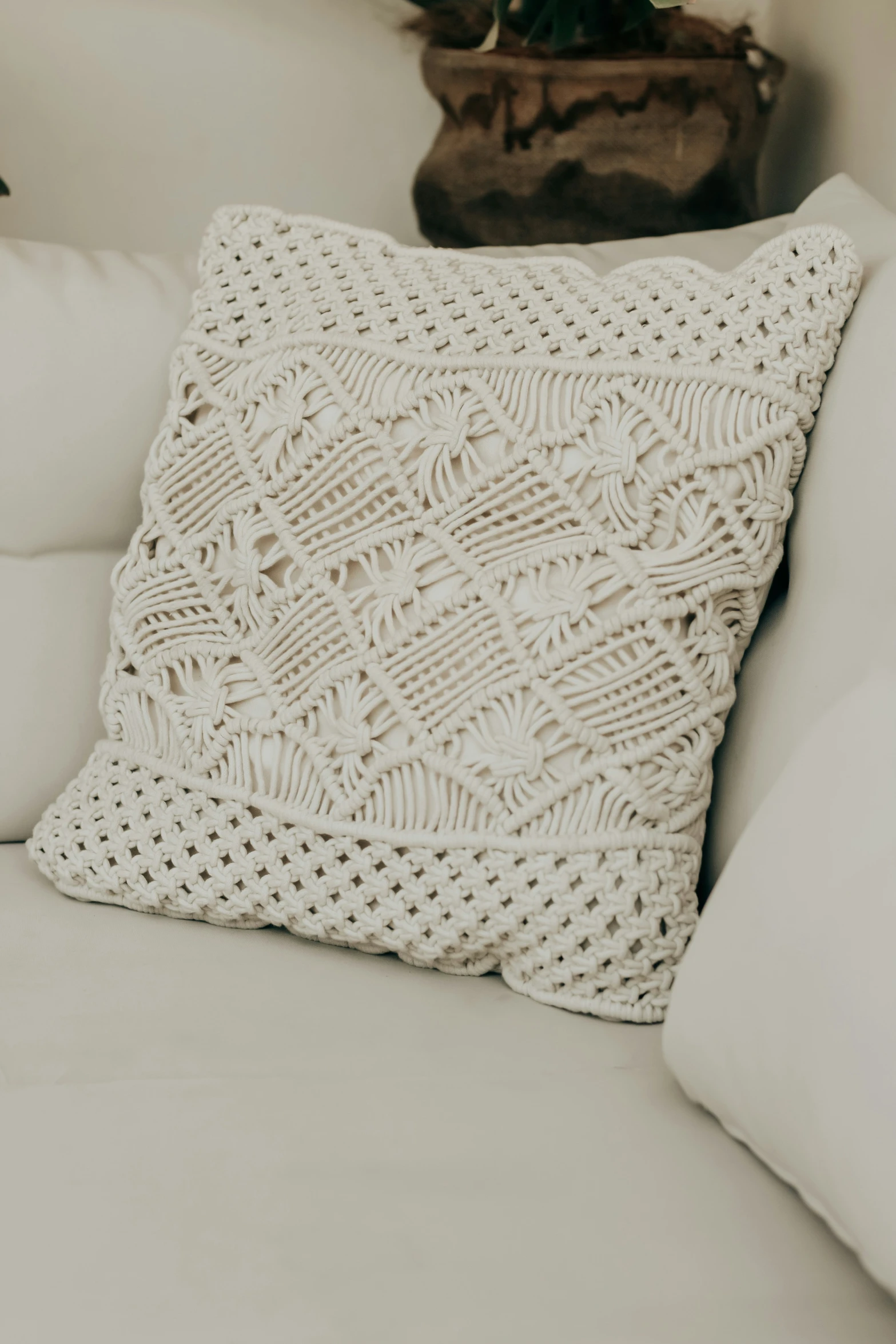 a white couch with an intricate crocheted throw pillow