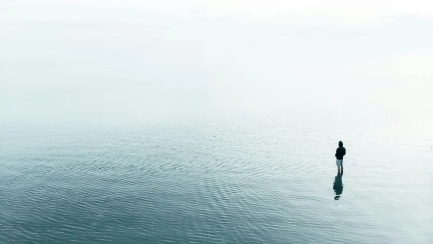 two people in water looking at horizon on cloudy day