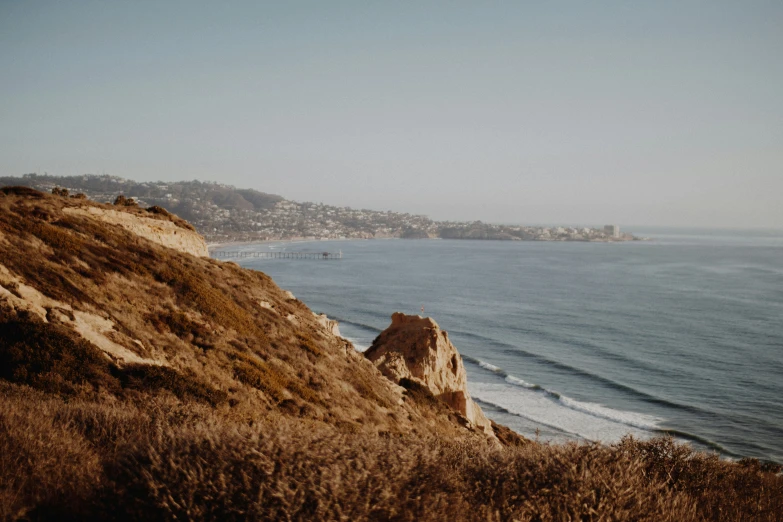 the coast next to a hill has waves coming in