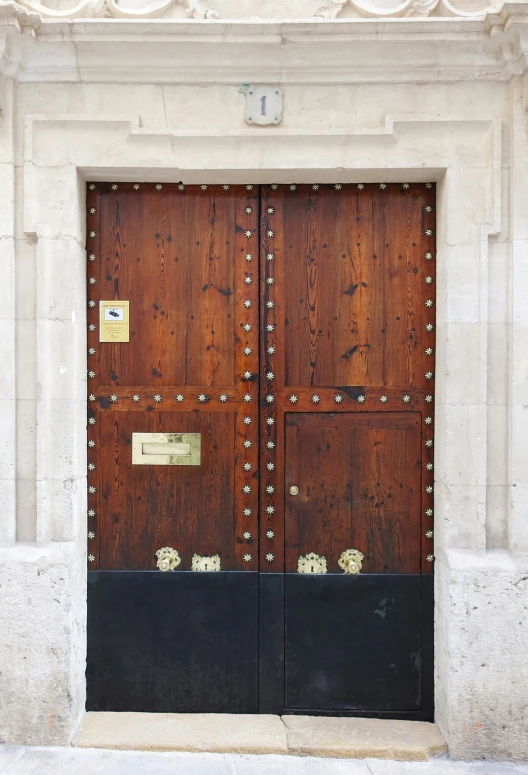 an old building has two wooden doors with gold rivets