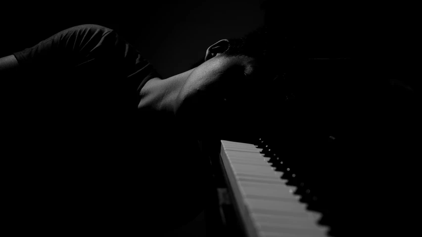 the man is resting his head on a piano