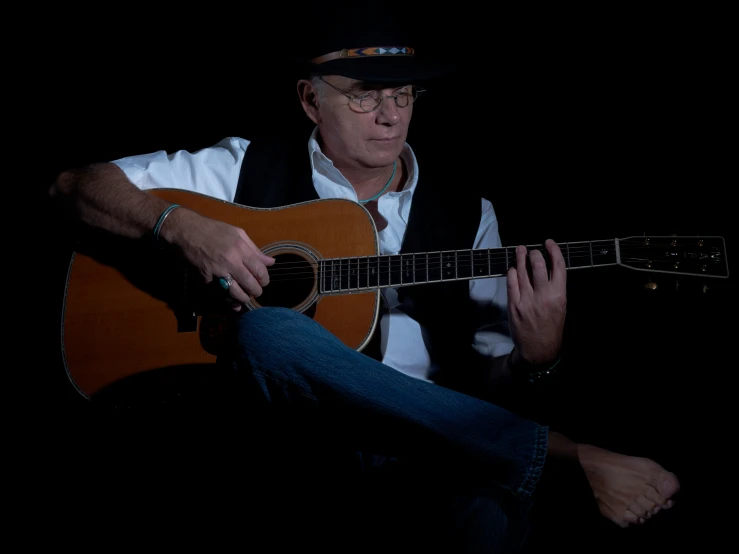 a man sitting down while playing a guitar