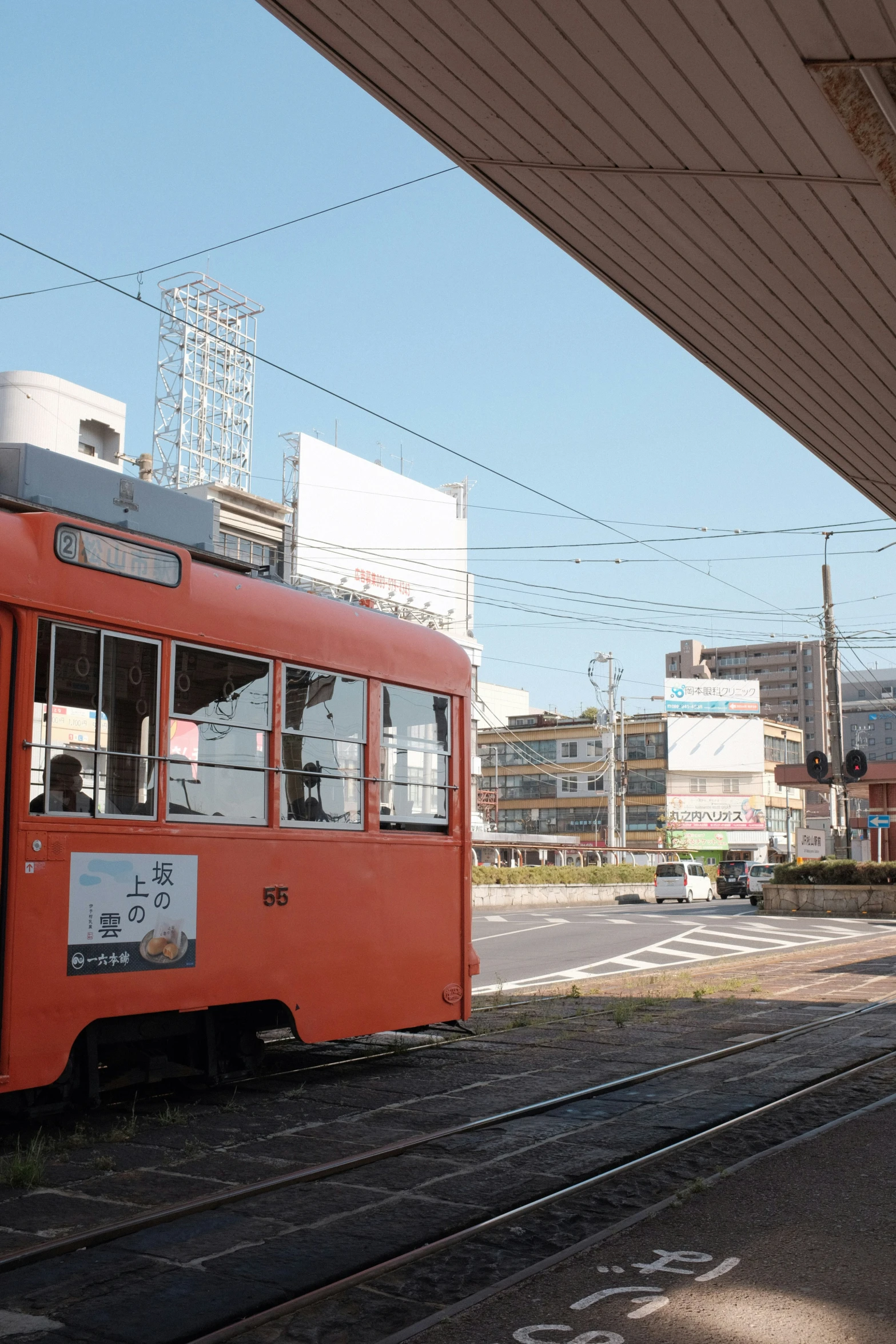 a red tram driving down a street next to a station