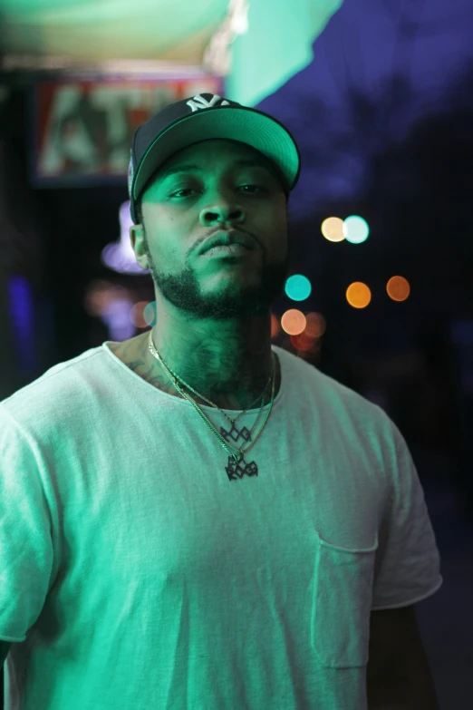 a man with green eyes wearing a white shirt and a cap