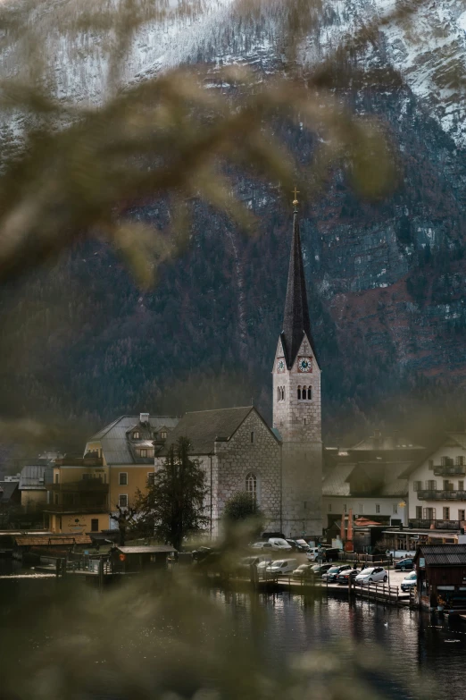 a white church with black clock tower with a mountain in the background