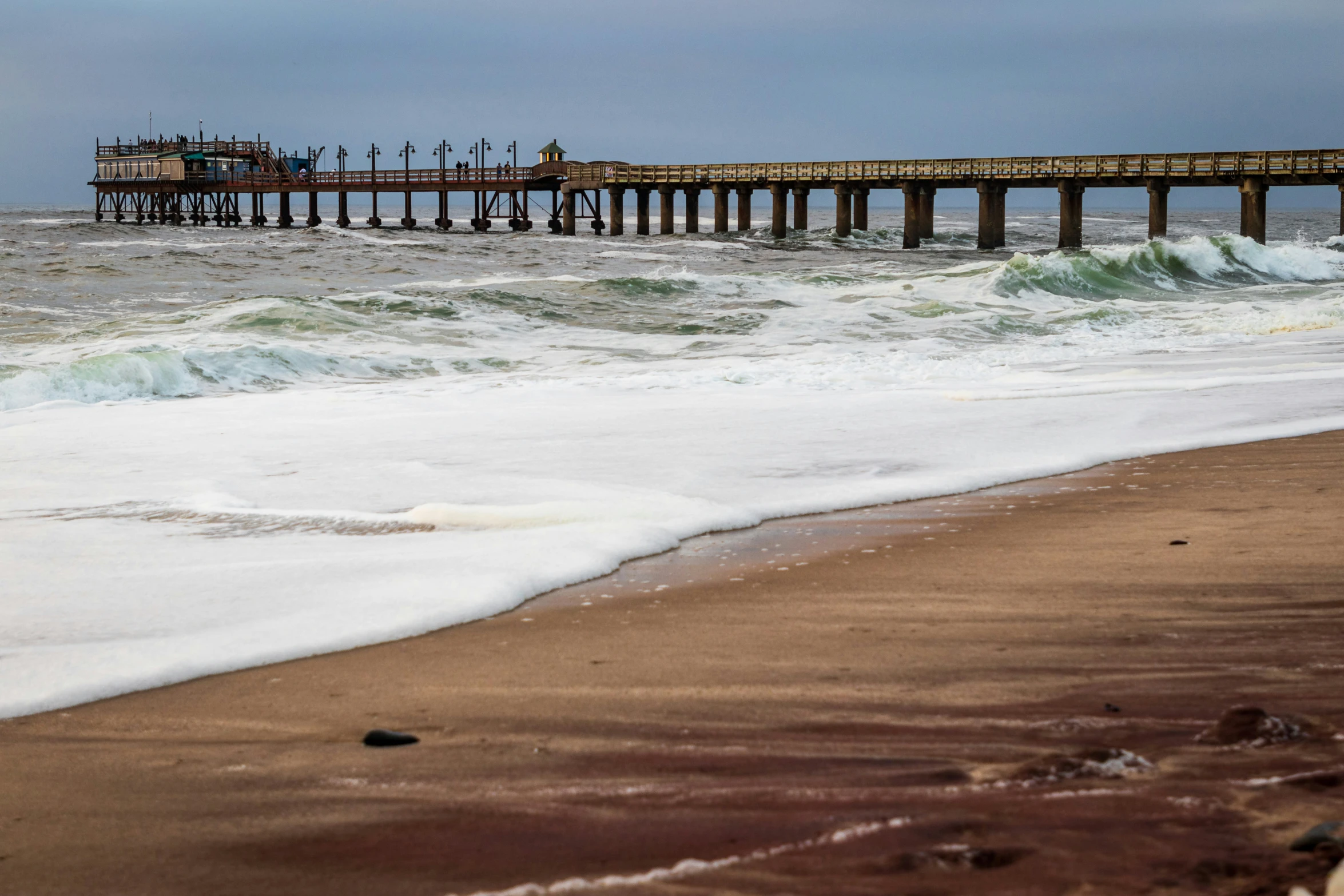 the pier on the ocean with waves coming in to shore