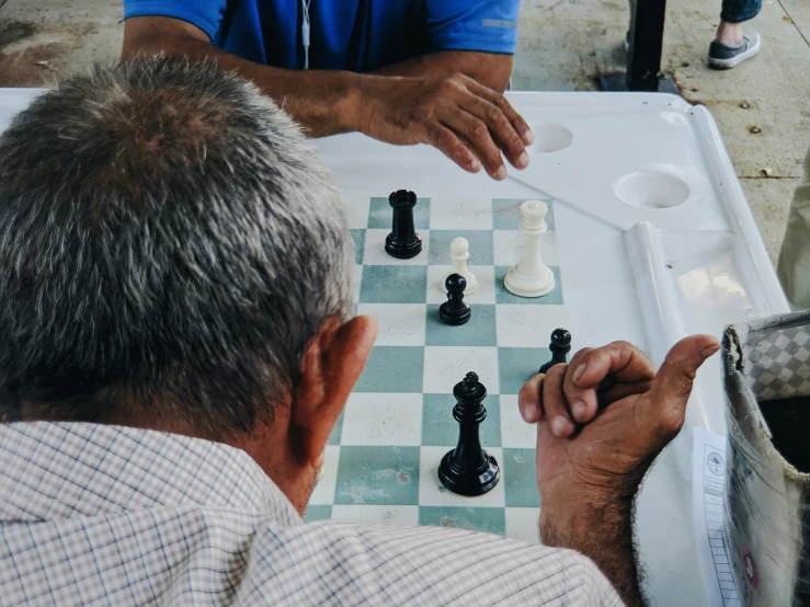 two men playing chess at an outdoor chess set