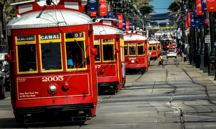 three red and yellow trolleys sitting on the side of the road