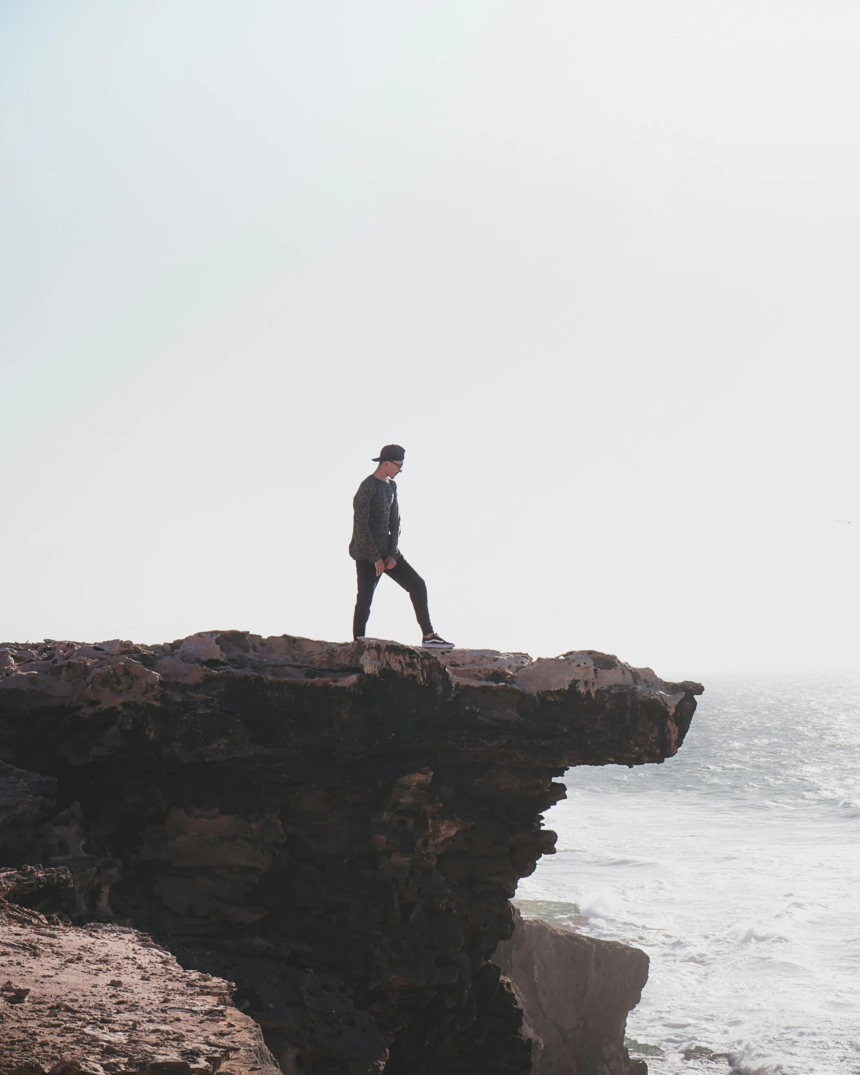 a person walking along an ocean cliff next to the sea