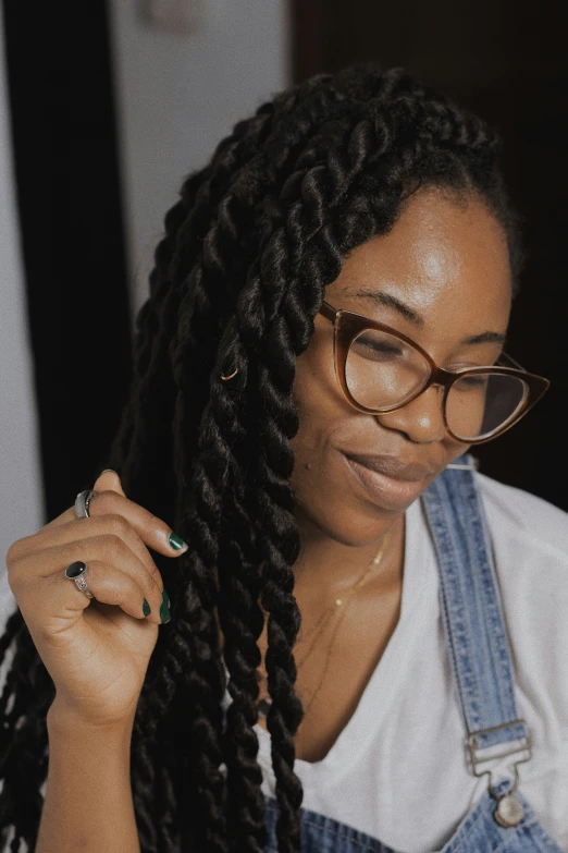 woman in overalls and large glasses looking down