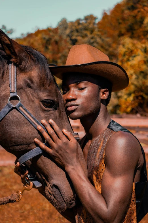 man in hat holding up to the nose of a horse