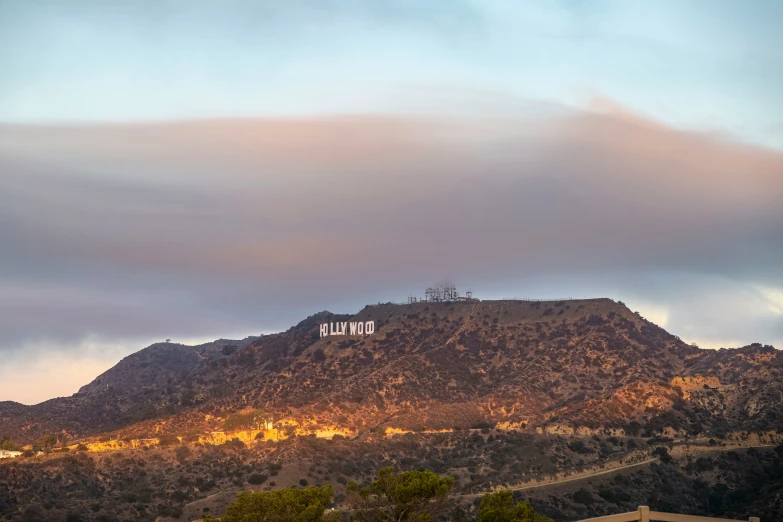 a hill top with writing on the side and mountains in the background