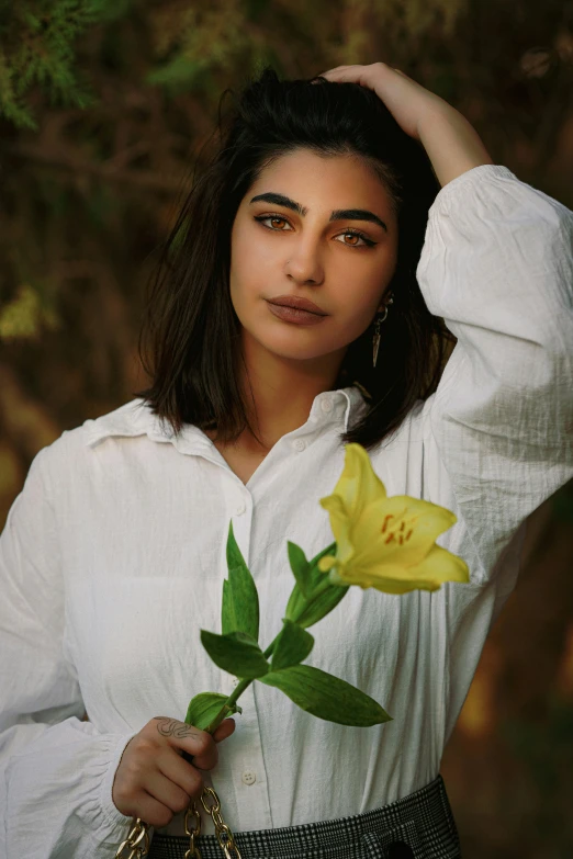 woman holding a flower with green leaves in her left hand