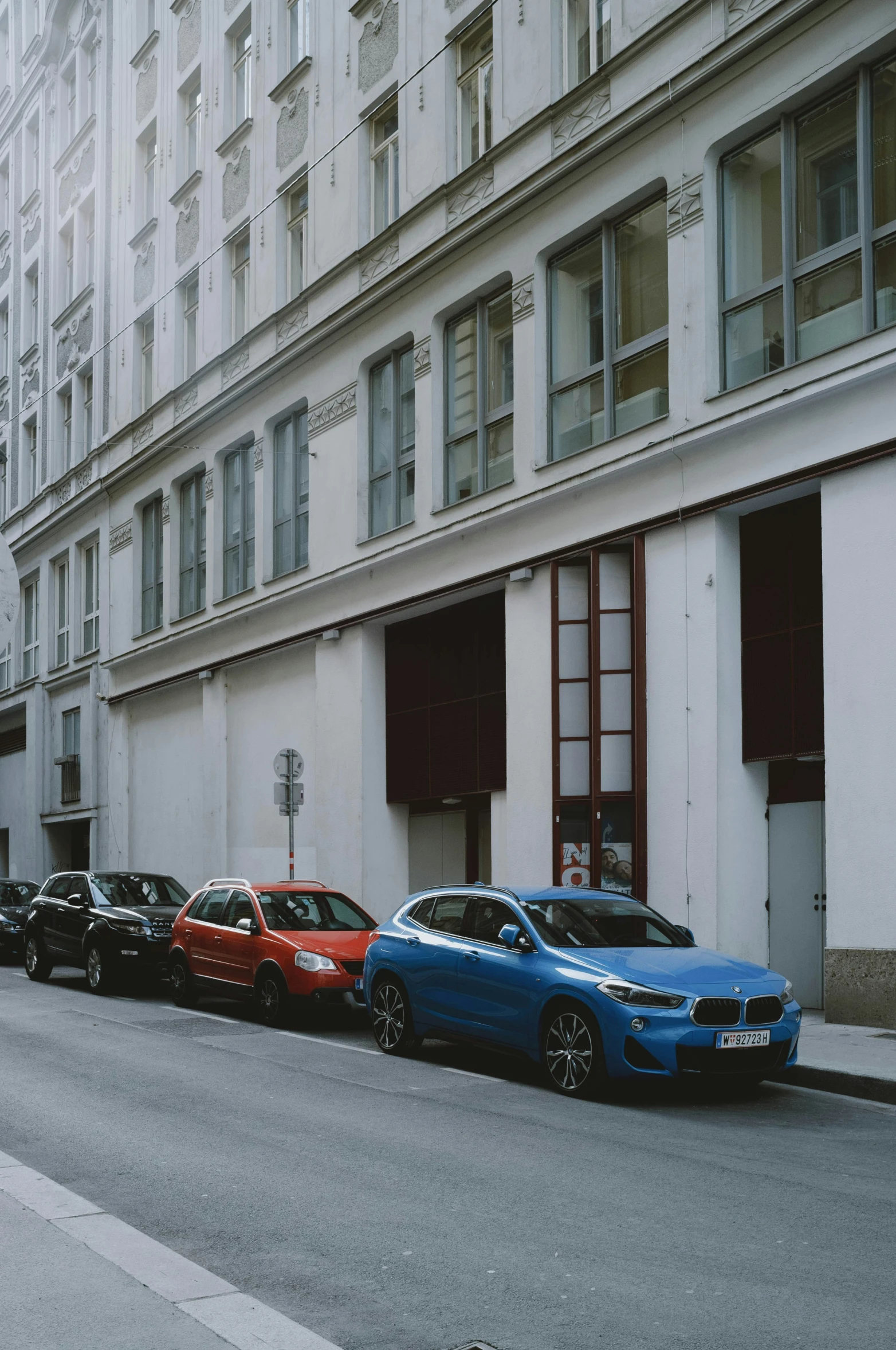 line of cars parked on street with building in background